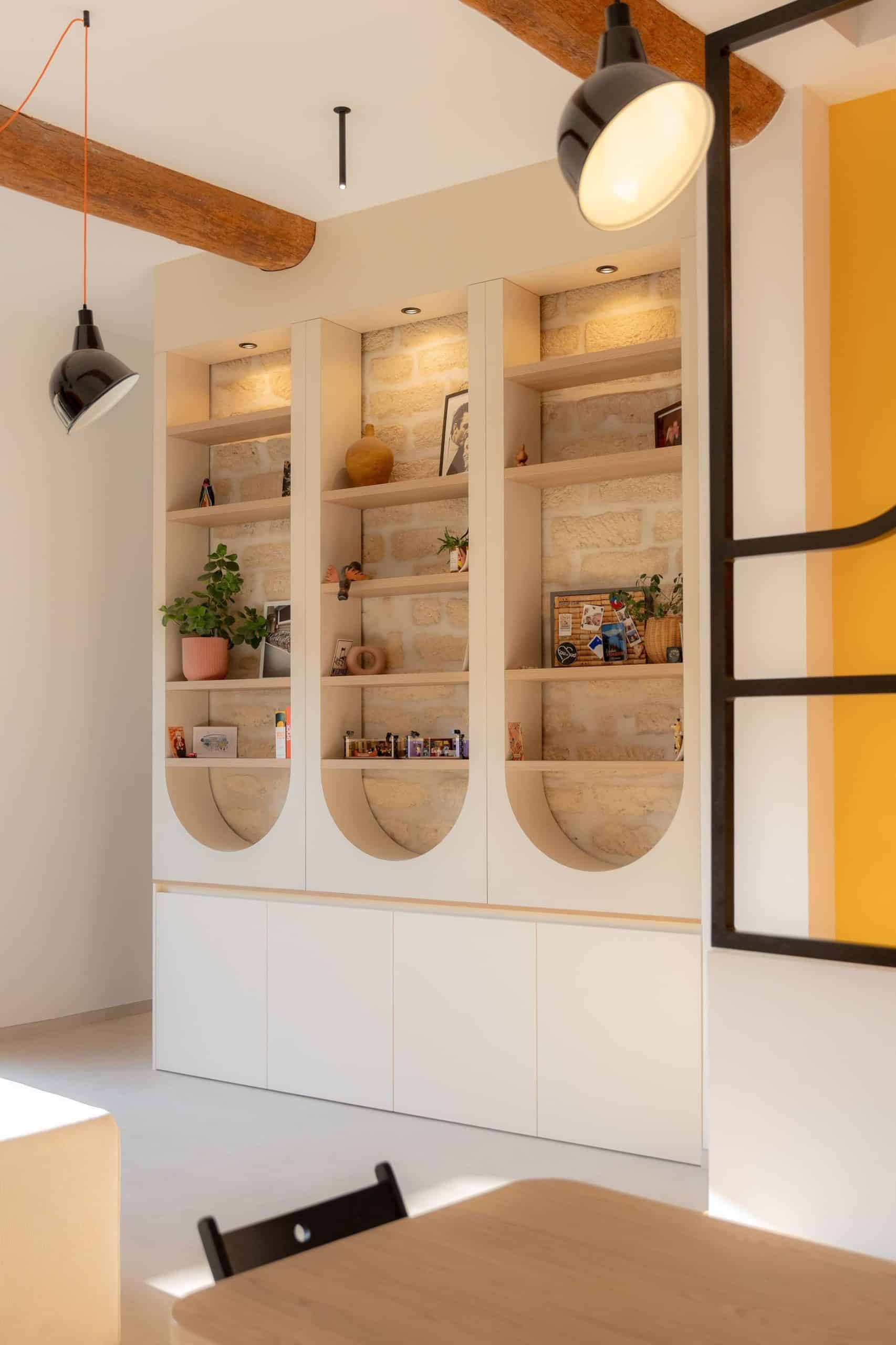 Bibliothèque sur mesure en pierre apparente et niches arrondies