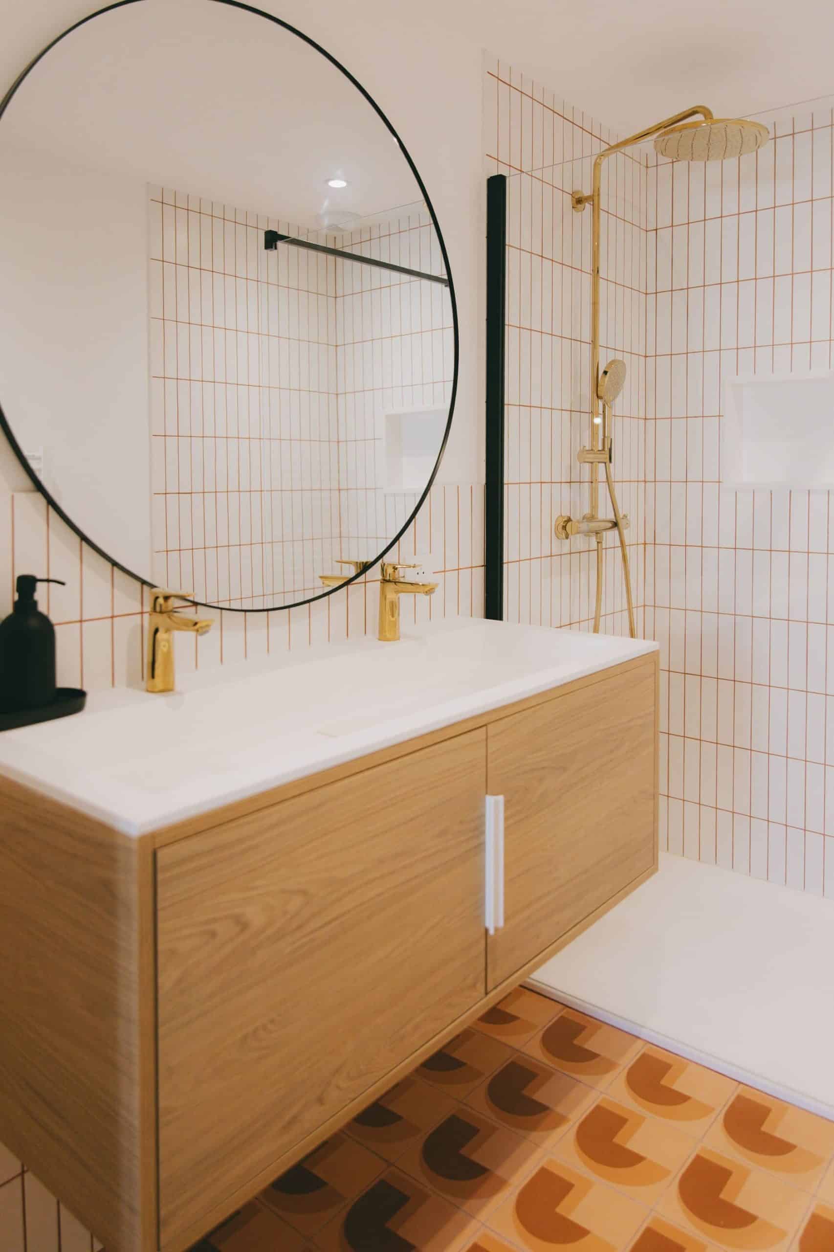 Salle de bain design avec robinetterie dorée et meuble bois clair – Montpellier