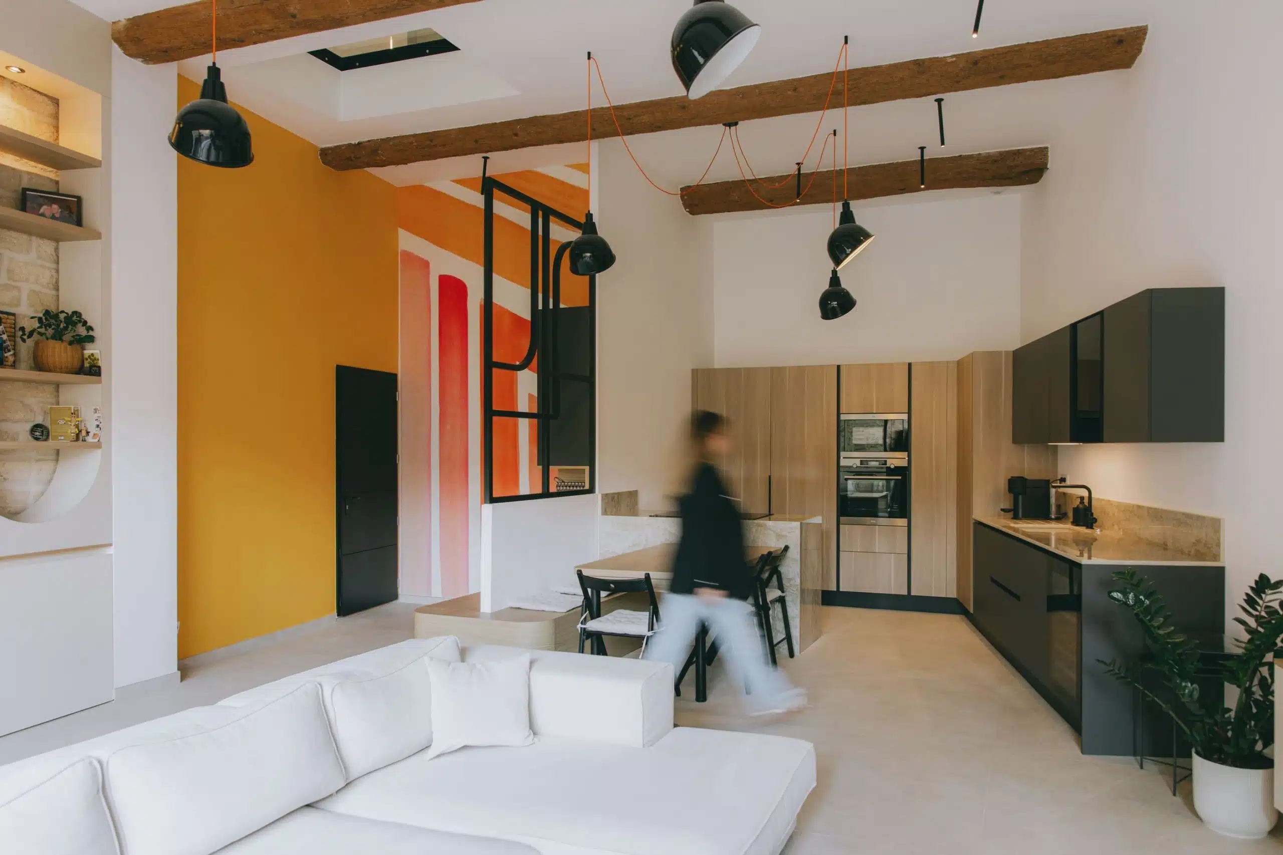 Vue d’ensemble salon et cuisine avec poutres apparentes