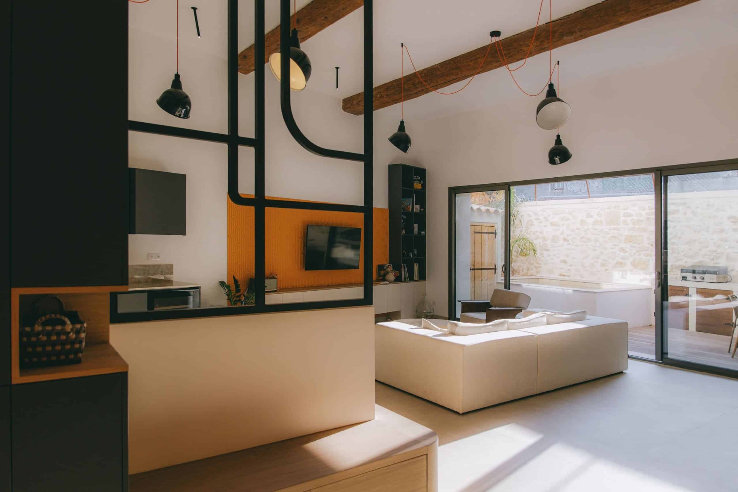 Salon lumineux avec murs en pierre et verrière moderne