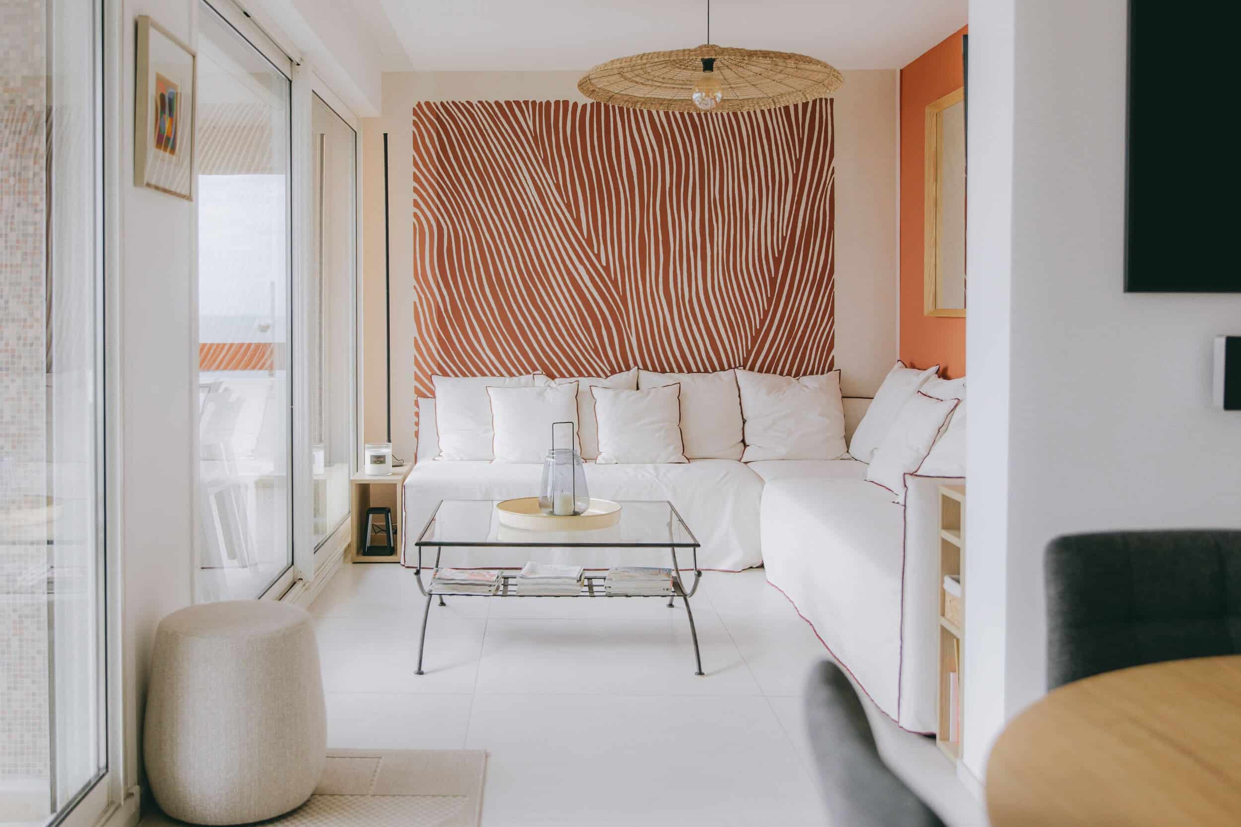 Salon avec mur graphique terracotta et canapé blanc – Appartement La Grande-Motte