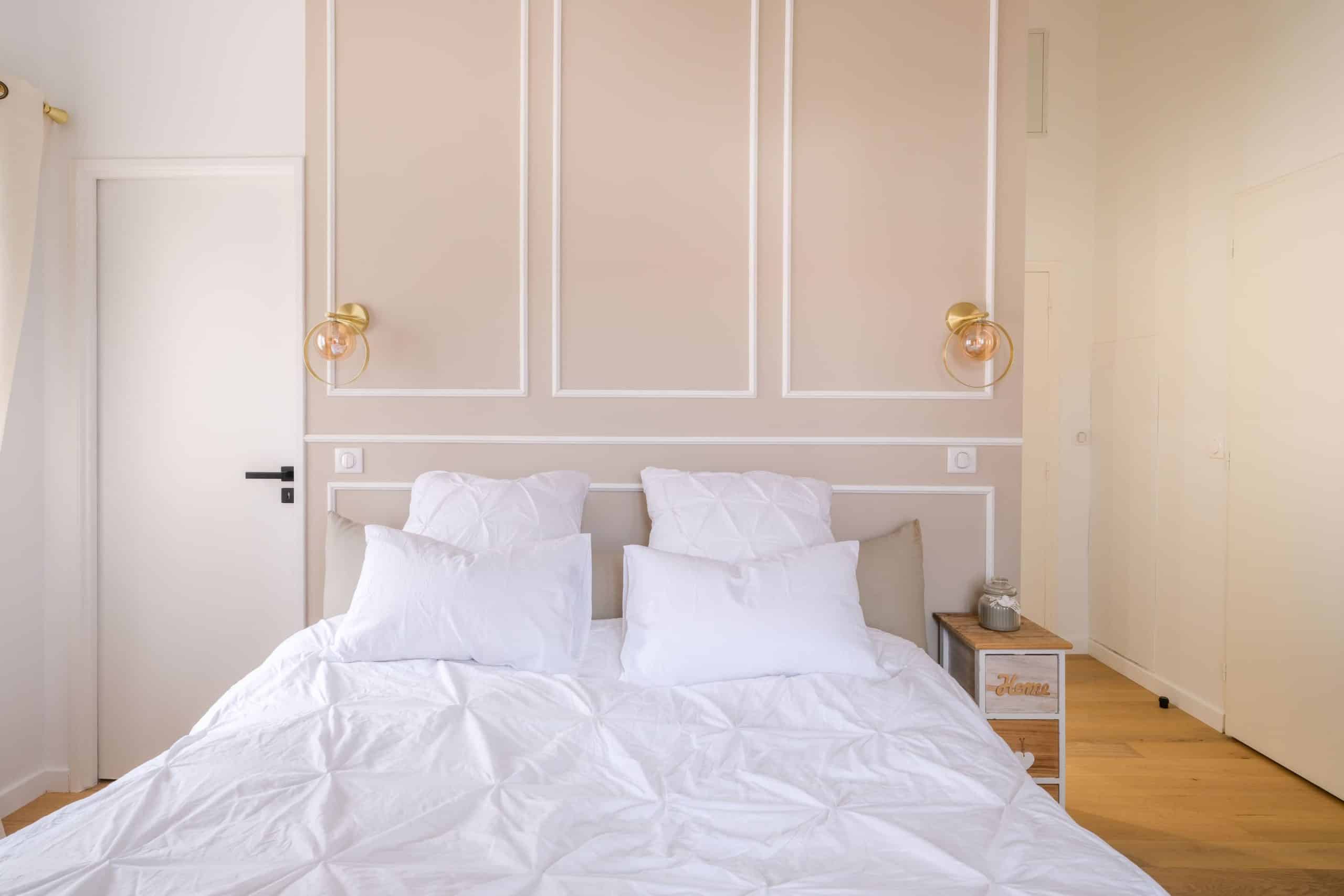 Chambre élégante beige avec moulures et éclairage doré