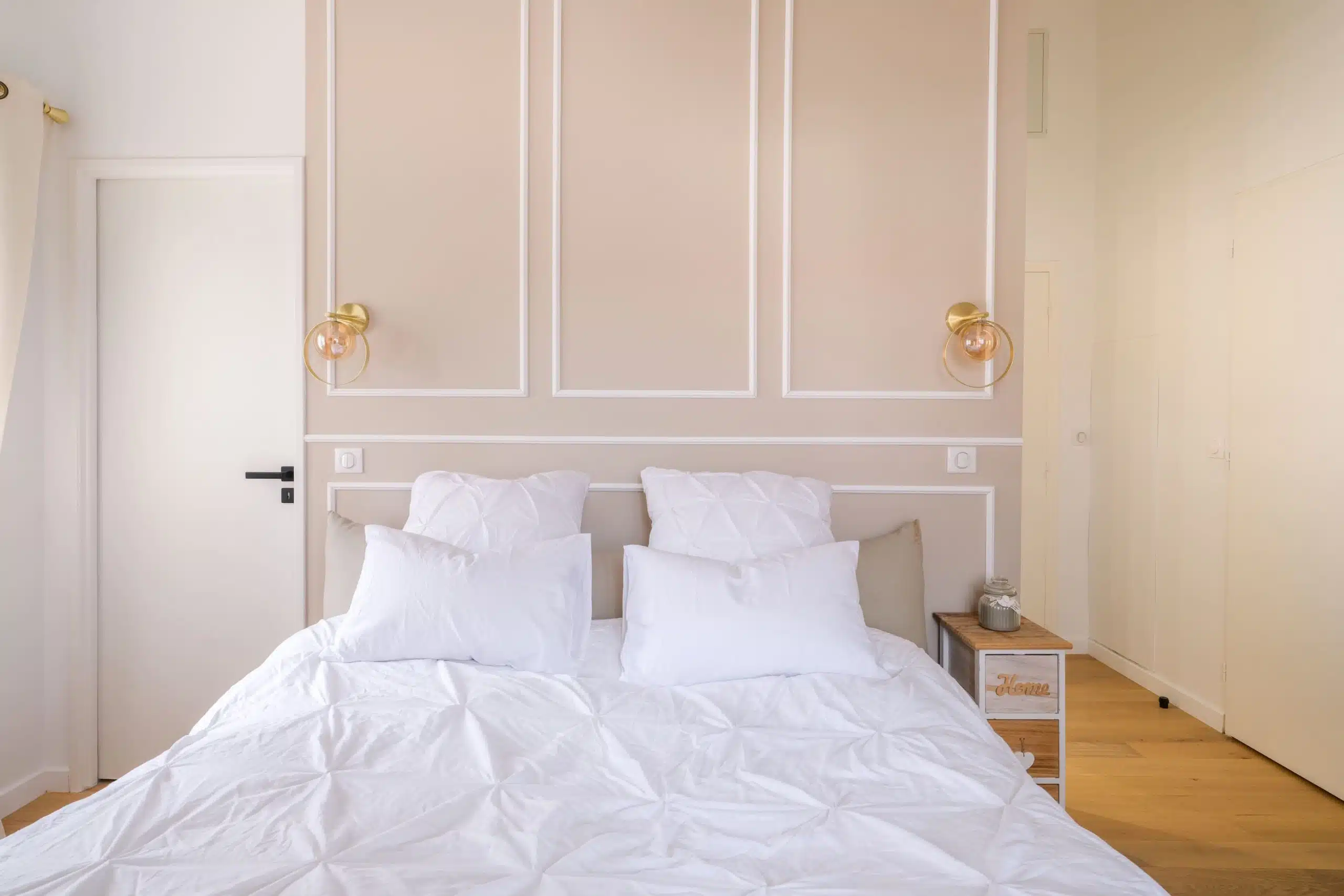 Chambre élégante beige avec moulures et éclairage doré