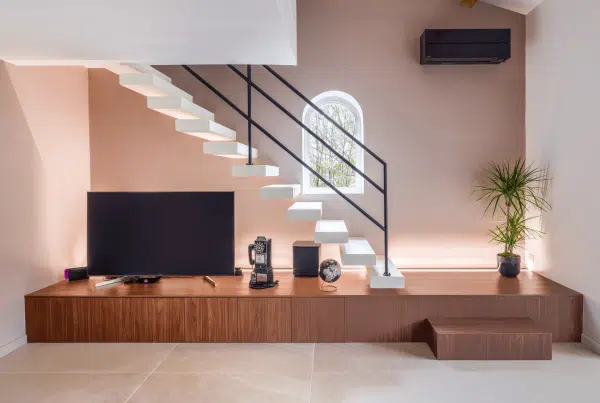 Salon contemporain avec escalier design, meuble TV sur mesure en bois et ambiance minimaliste chaleureuse