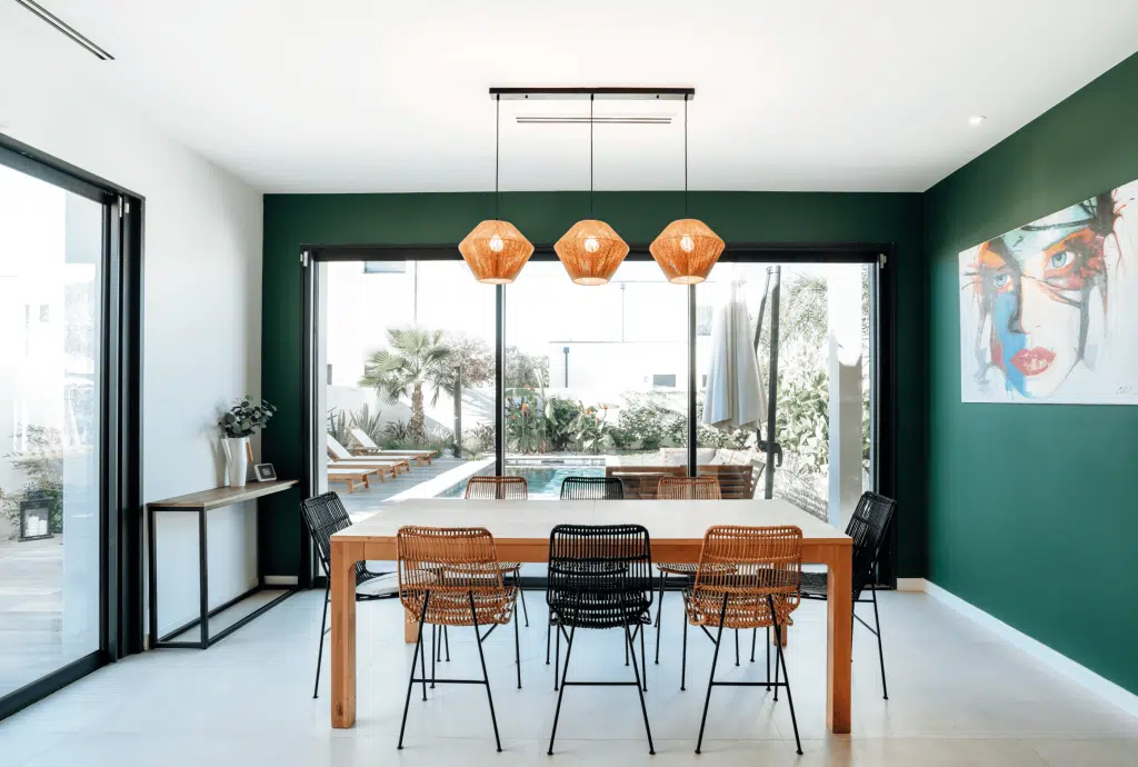 séjour salle à manger murs verts avec vue sur la piscine par l'agence Dugas à Montpellier