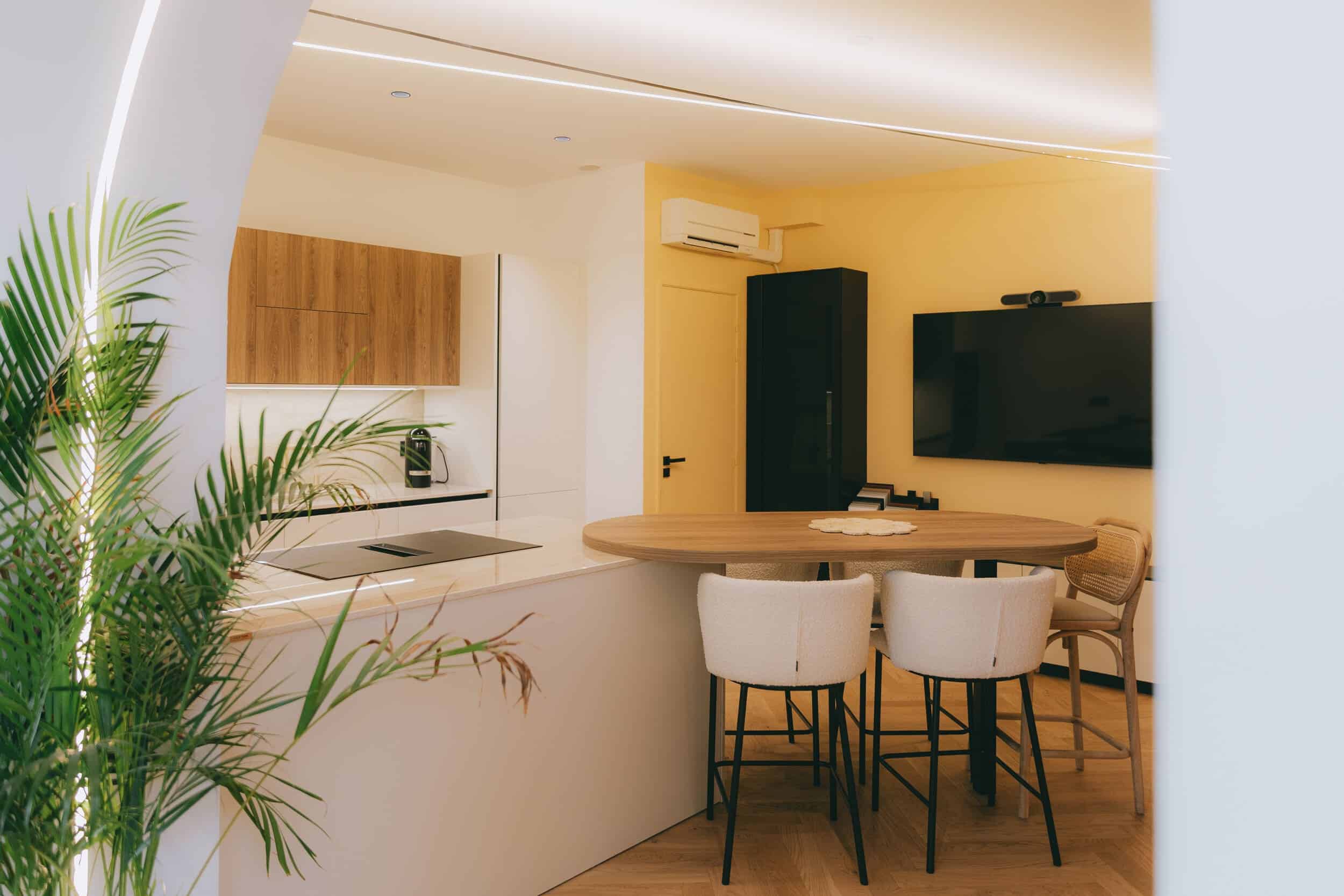 Cuisine ouverte réalisée par Jeremy Dugas, architecte d'intérieur, avec îlot central, table intégrée, éclairage architectural et finitions haut de gamme.