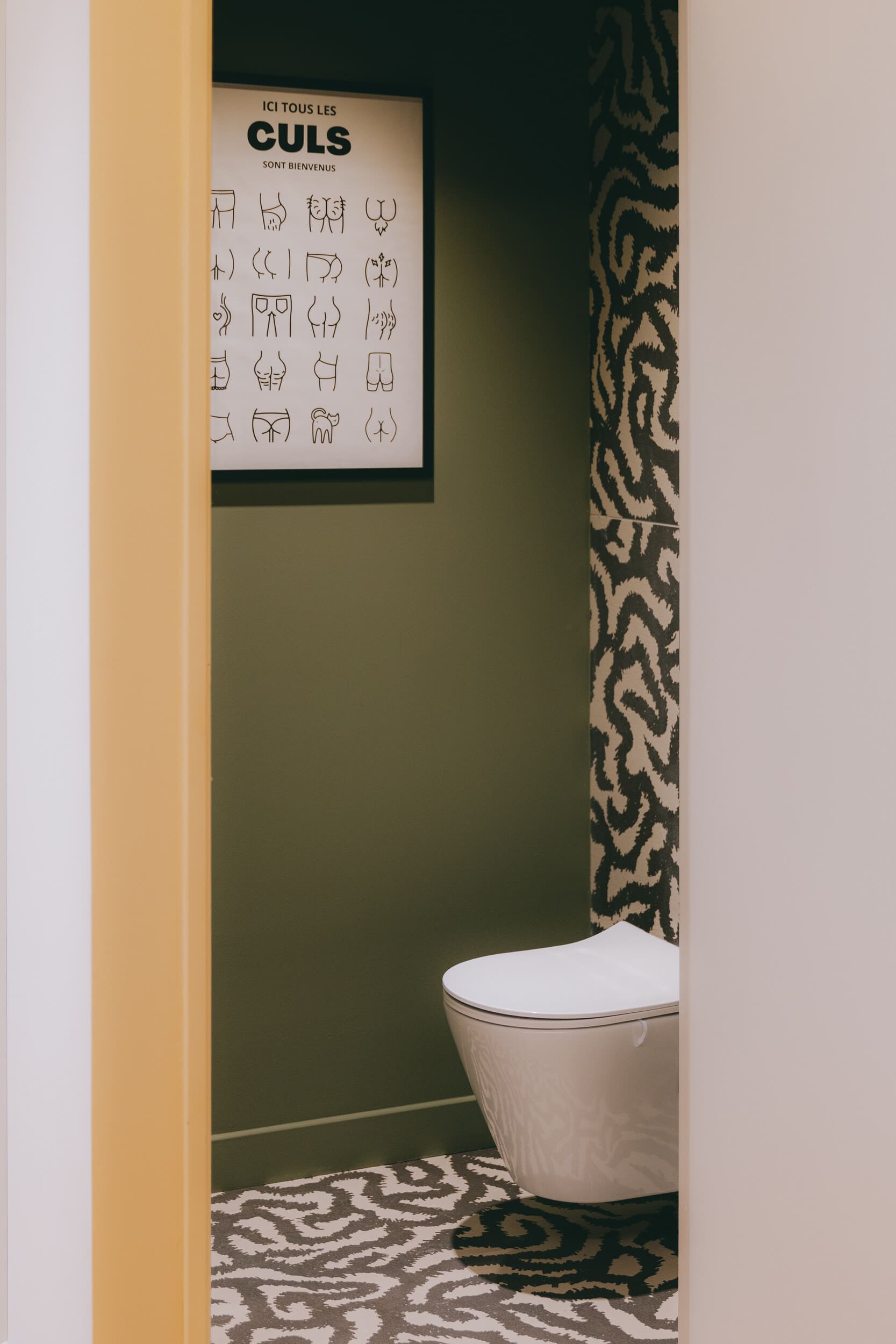 Aménagement de toilettes contemporaines mêlant couleurs profondes, revêtement graphique et décoration décalée imaginé par Jeremy Dugas