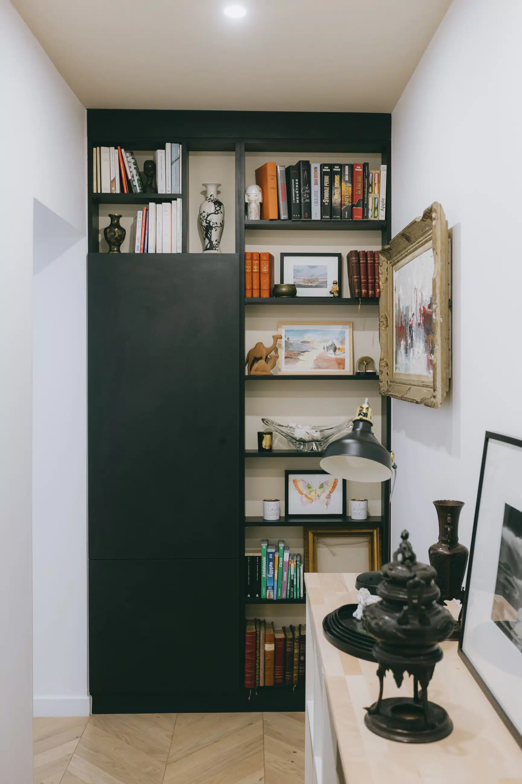 Bibliothèque sur mesure noire intégrée dans l'entrée, parquet en point de Hongrie