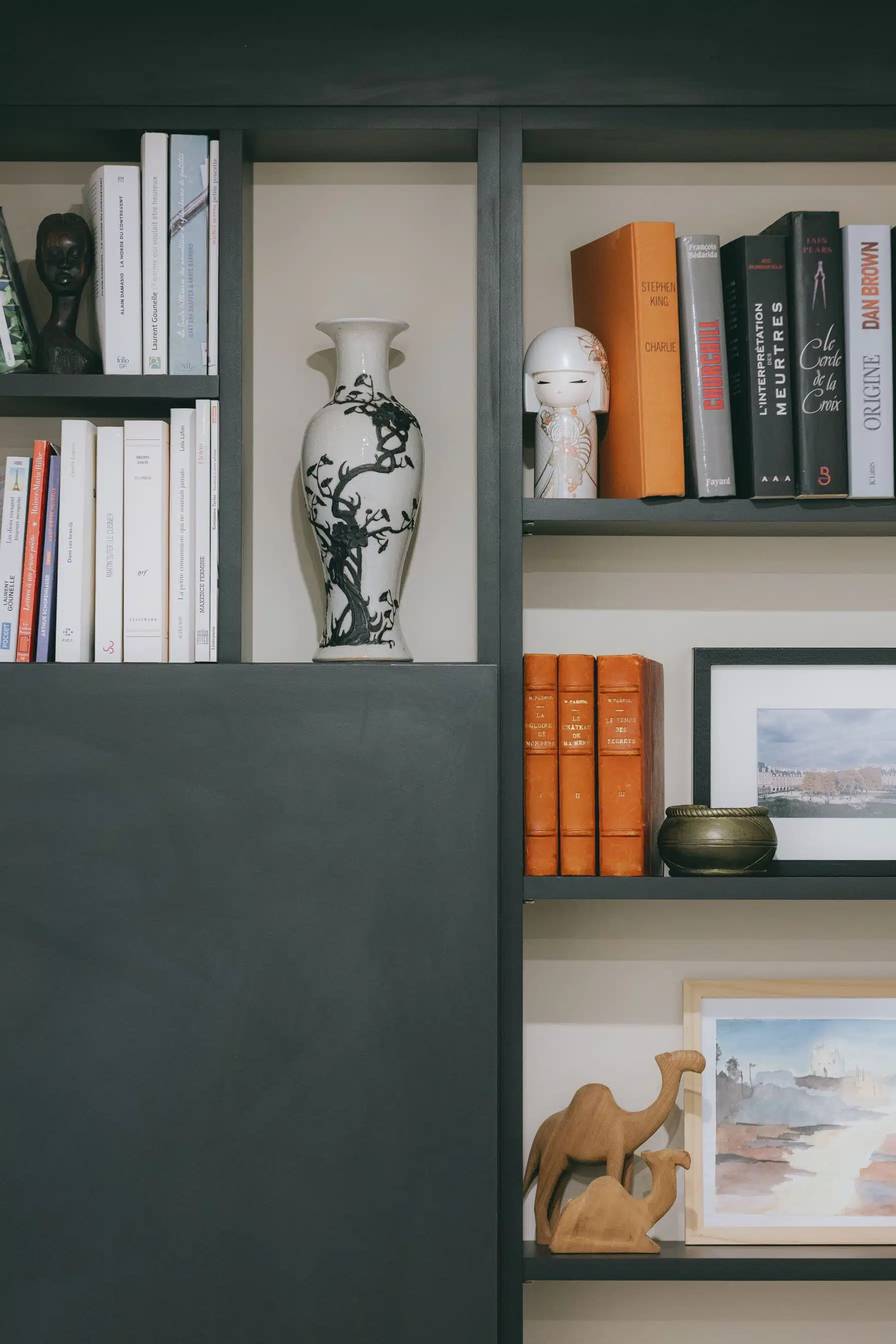 Détail des étagères noires de la bibliothèque avec livres et objets décoratifs