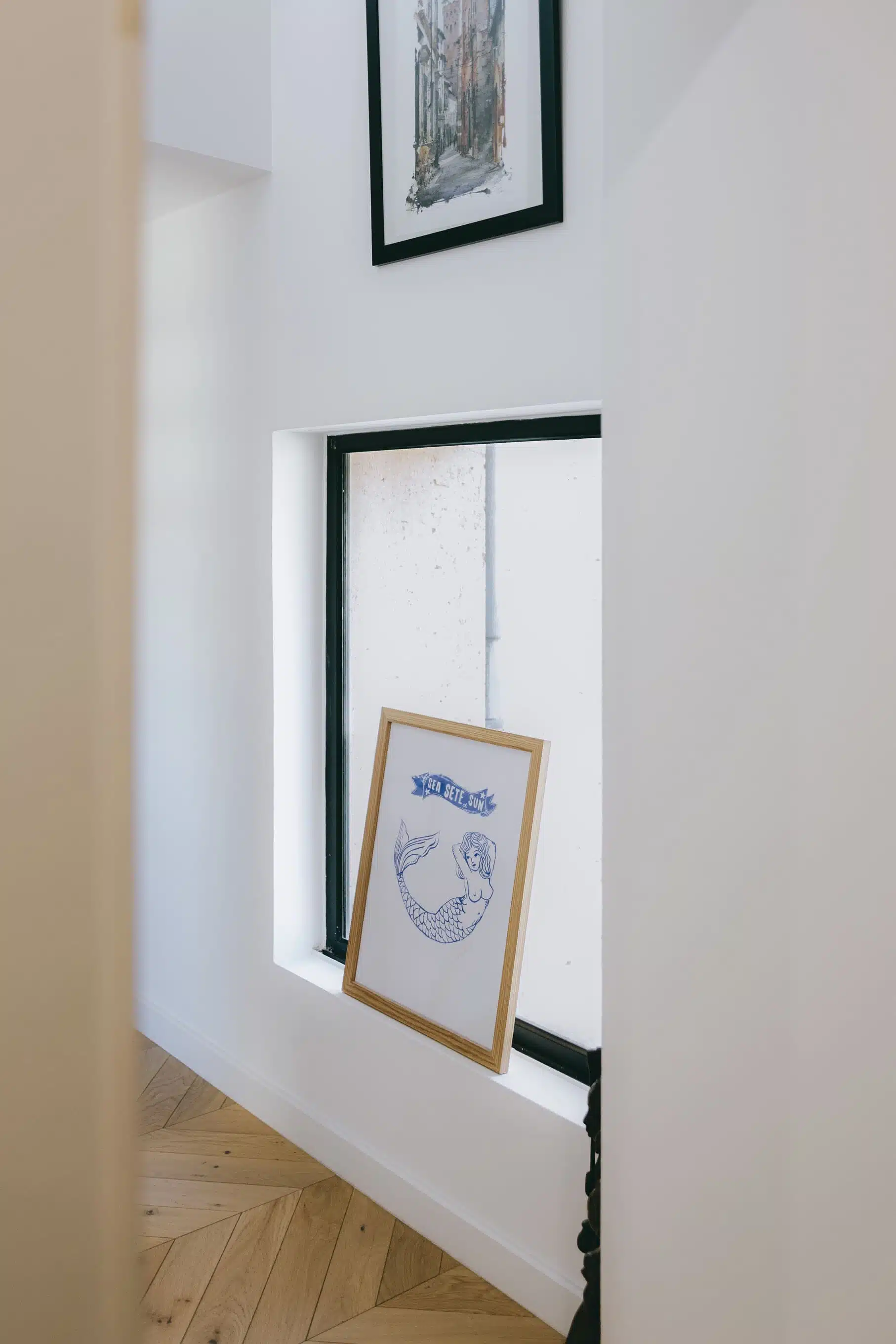 Fenêtre intérieure à cadre noir dans un couloir blanc