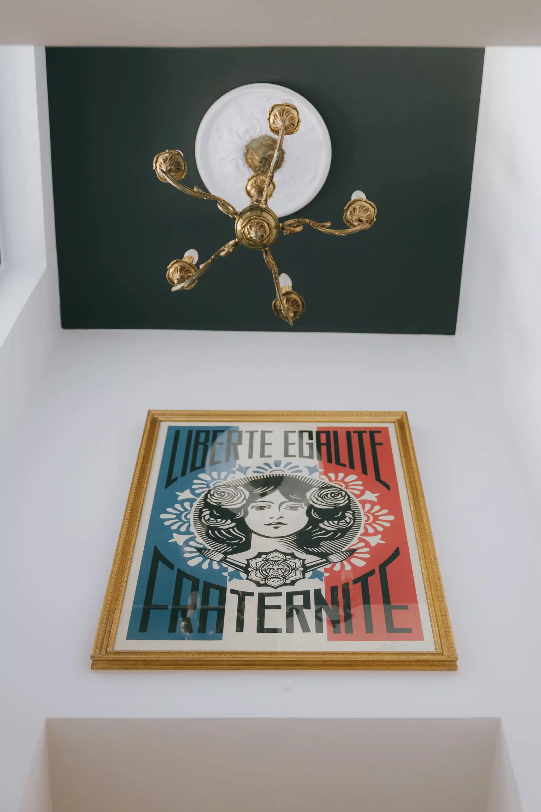 Plafond peint en noir avec lustre en laiton au-dessus d'une affiche encadrée