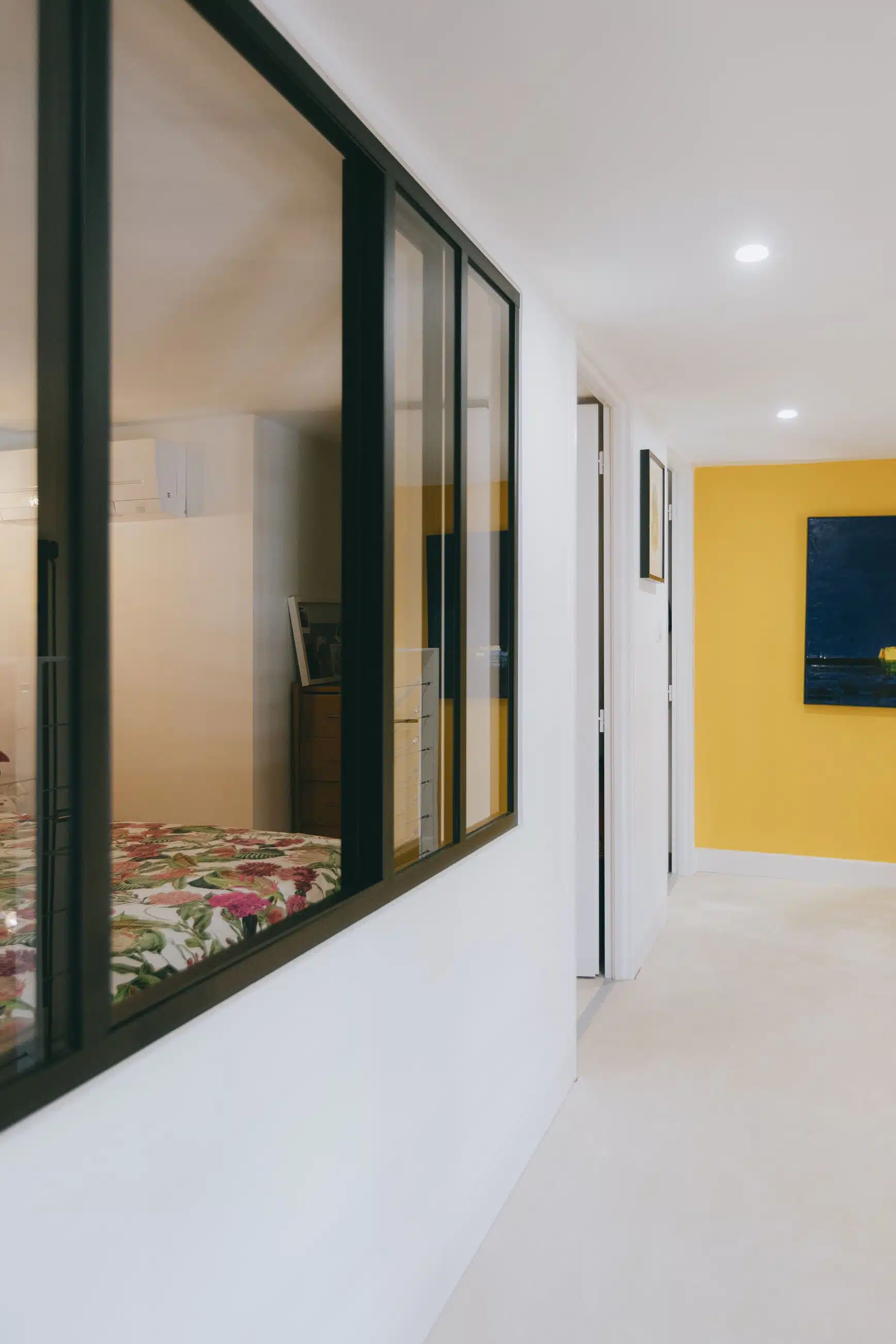 Chambre séparée du couloir par une verrière d'atelier à cadre noir