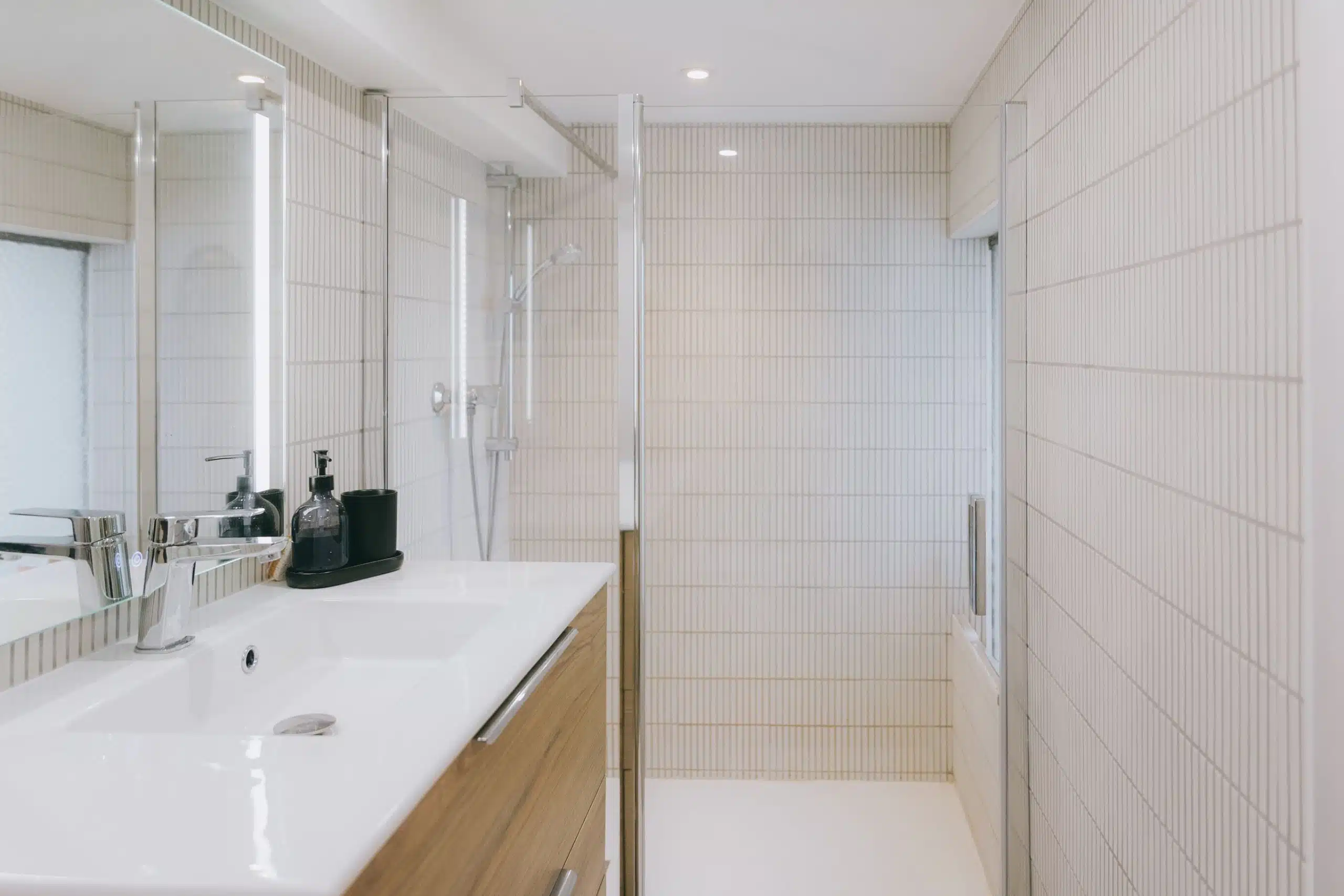 Salle de bain blanche avec vasque suspendue, meuble bois et douche à l'italienne
